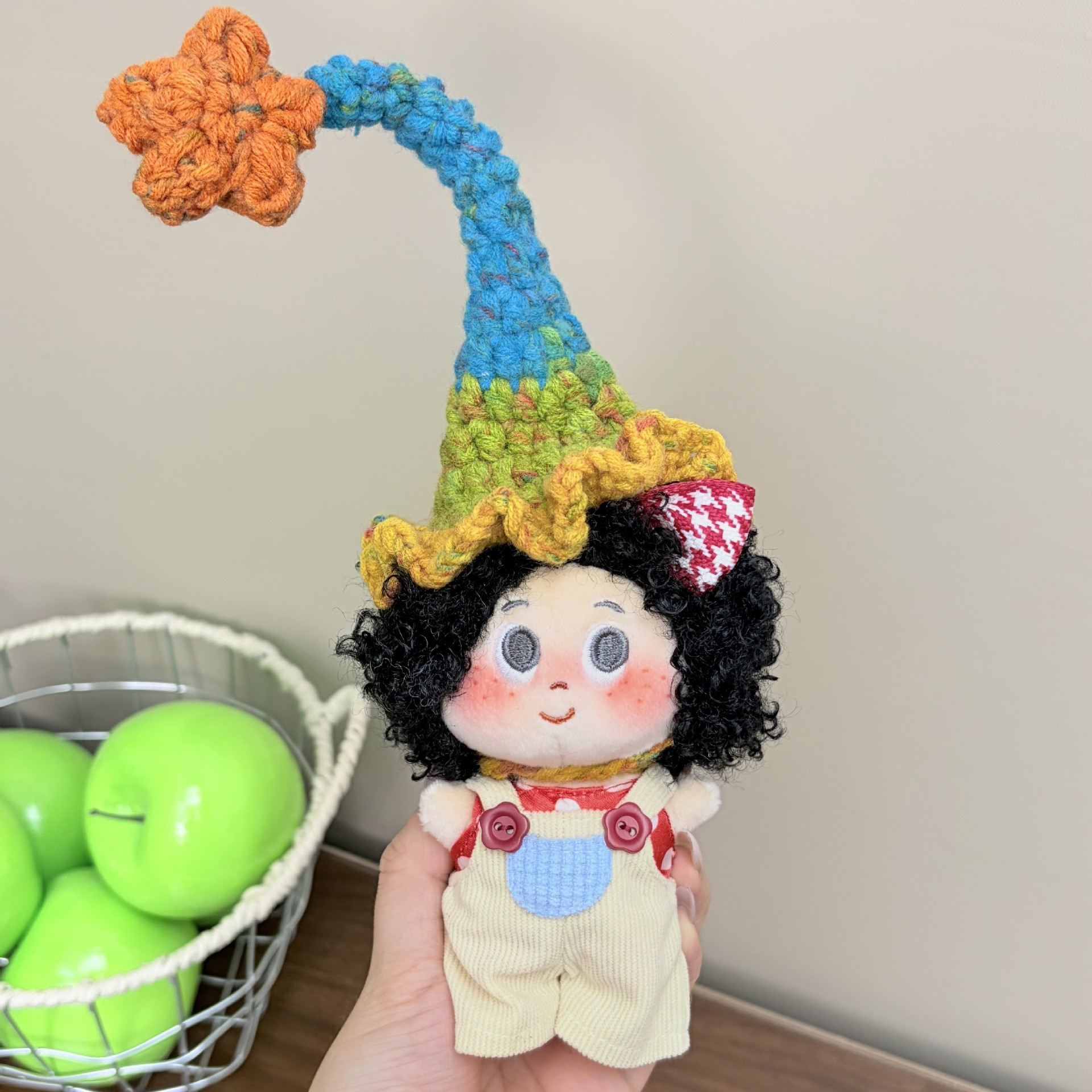 Supplied product photograph: black curly-haired doll with a star-topped pointed hat. Style reference 1; outfit and hat details vary.