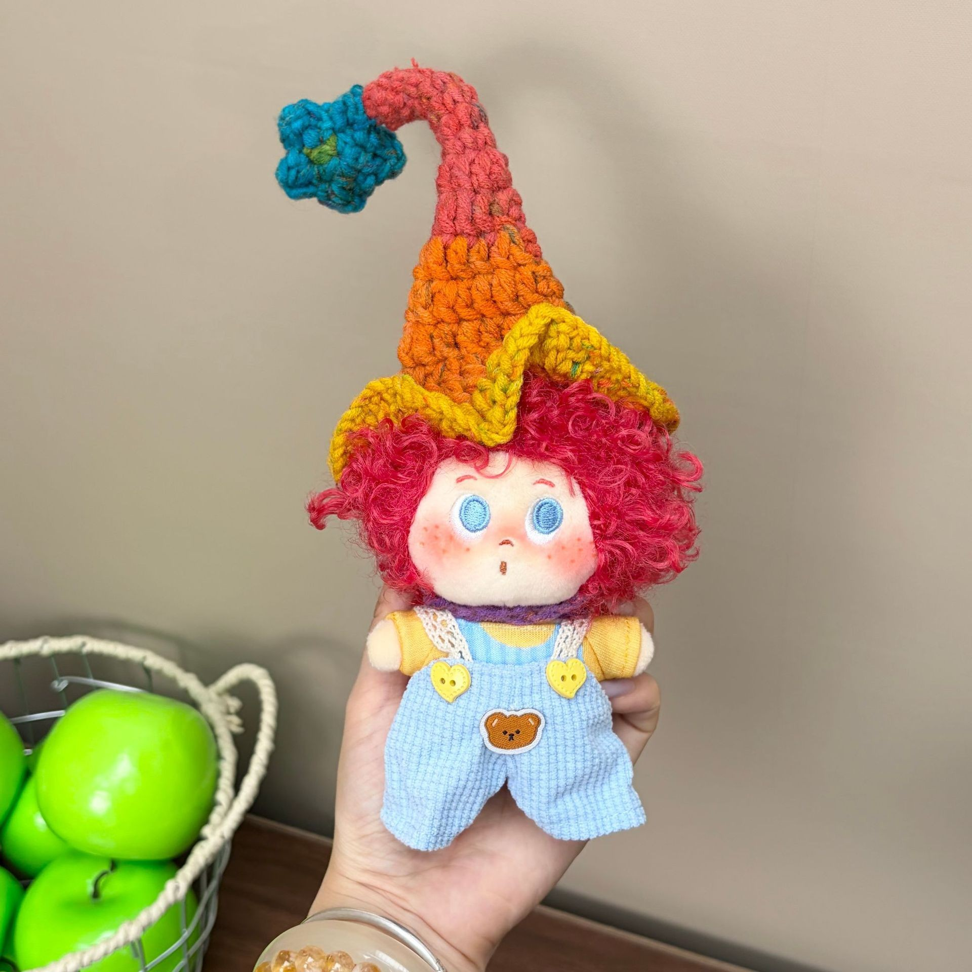 Supplied product photograph: red curly-haired doll with a star-topped pointed hat. Style reference 1; outfit and hat details vary.