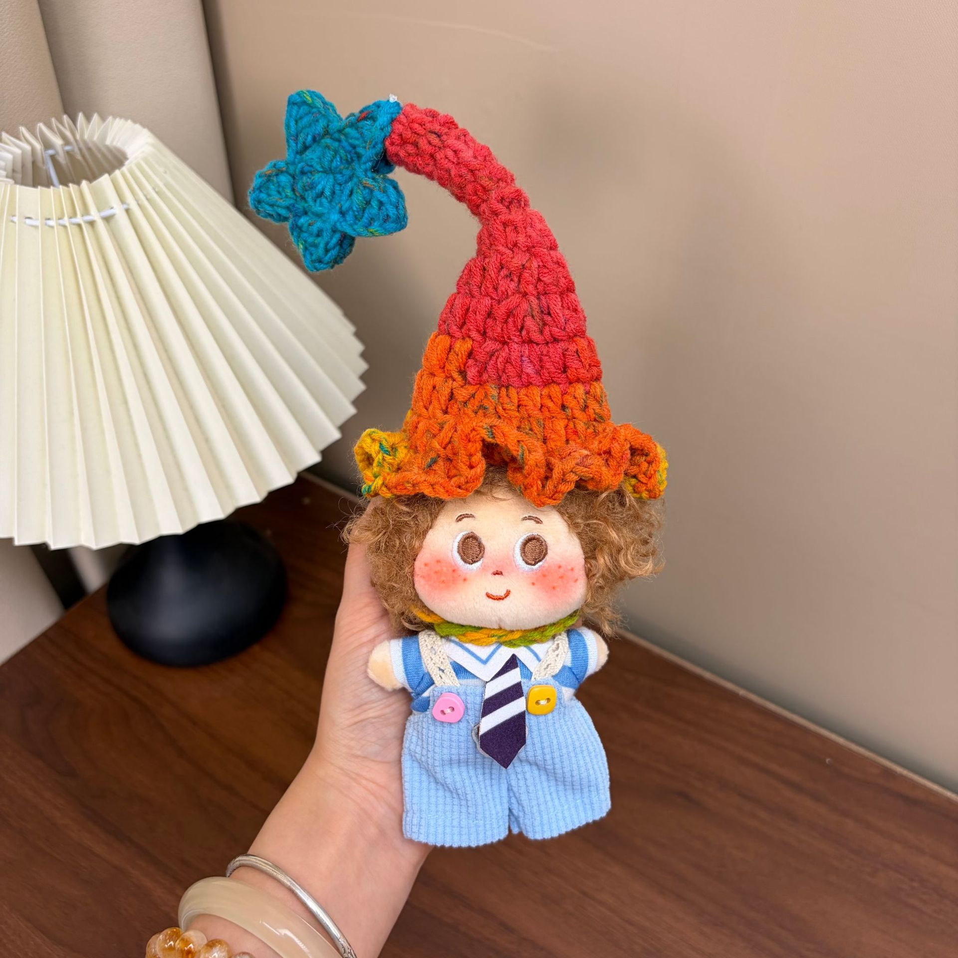 Supplied product photograph: sandy curly-haired doll with a star-topped pointed hat. Style reference 1; outfit and hat details vary.