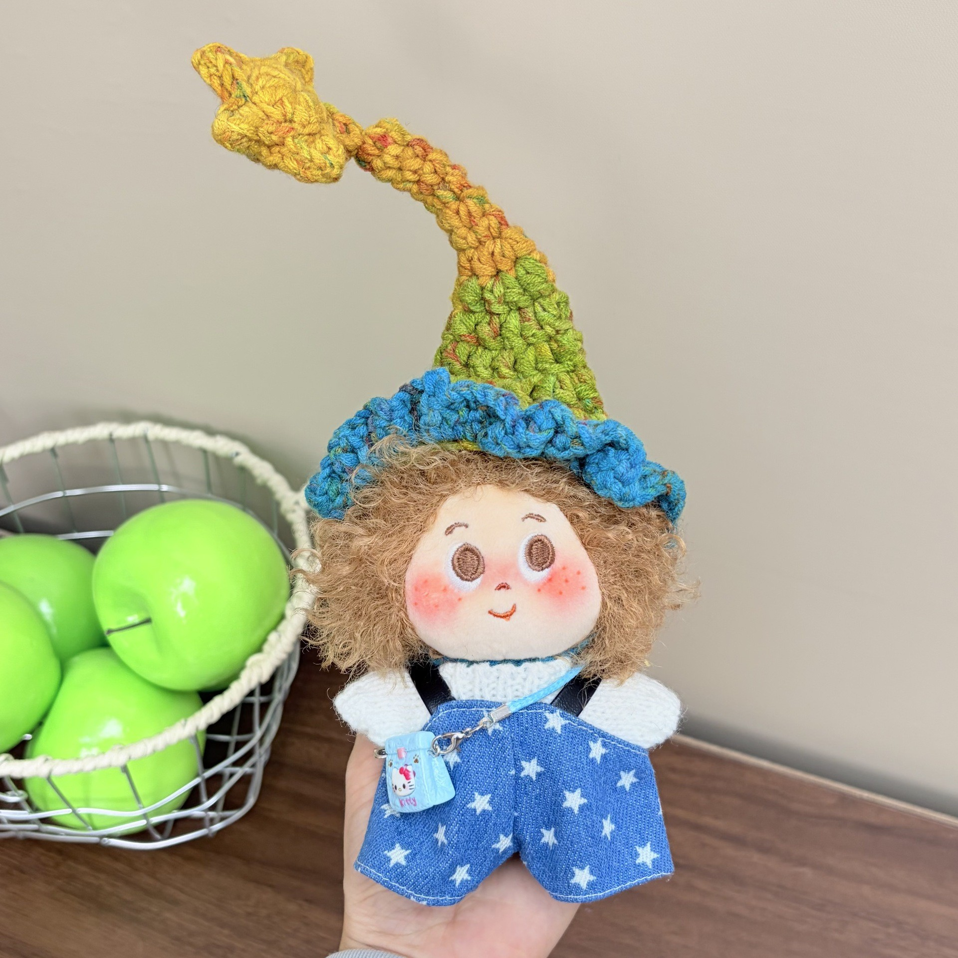 Supplied product photograph: sandy curly-haired doll with a star-topped pointed hat. Style reference 2; outfit and hat details vary.